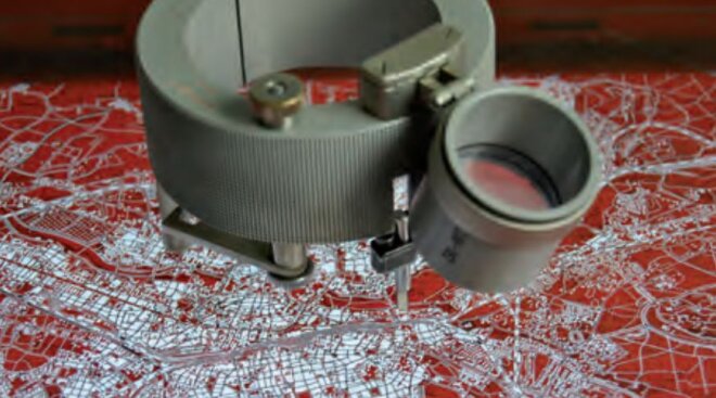 Grauer Metallring mit Stichel auf einer Glasplatte mit roter Zeichnung
